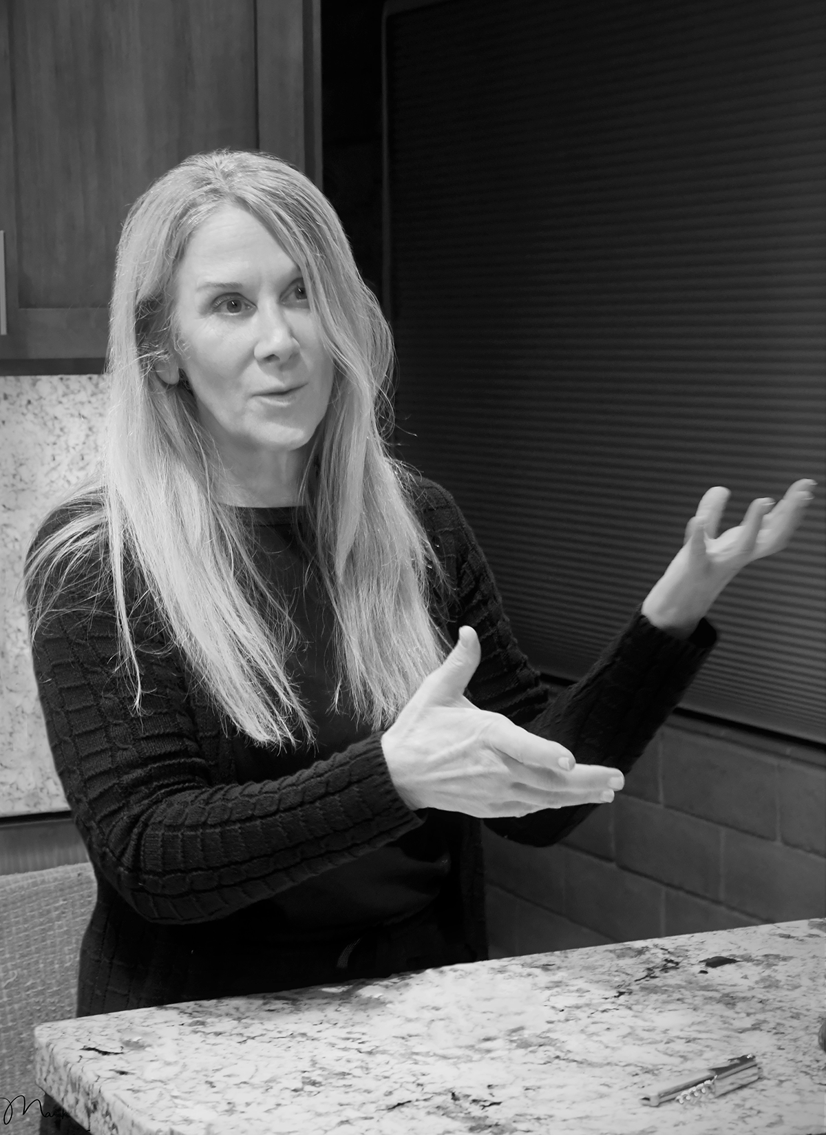 Black and white photo of Juliane Grosso Kresser talking and gesturing toward a wine bottle.